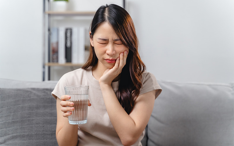 Woman experiencing persistent tooth pain after a root canal procedure.