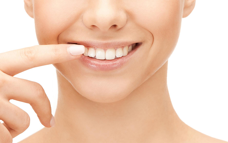 Woman pointing to healthy teeth to identify tooth decay.