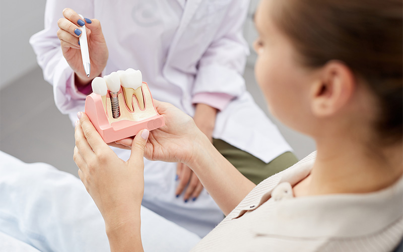 Elite Dental dentist explaining implant model to patient.